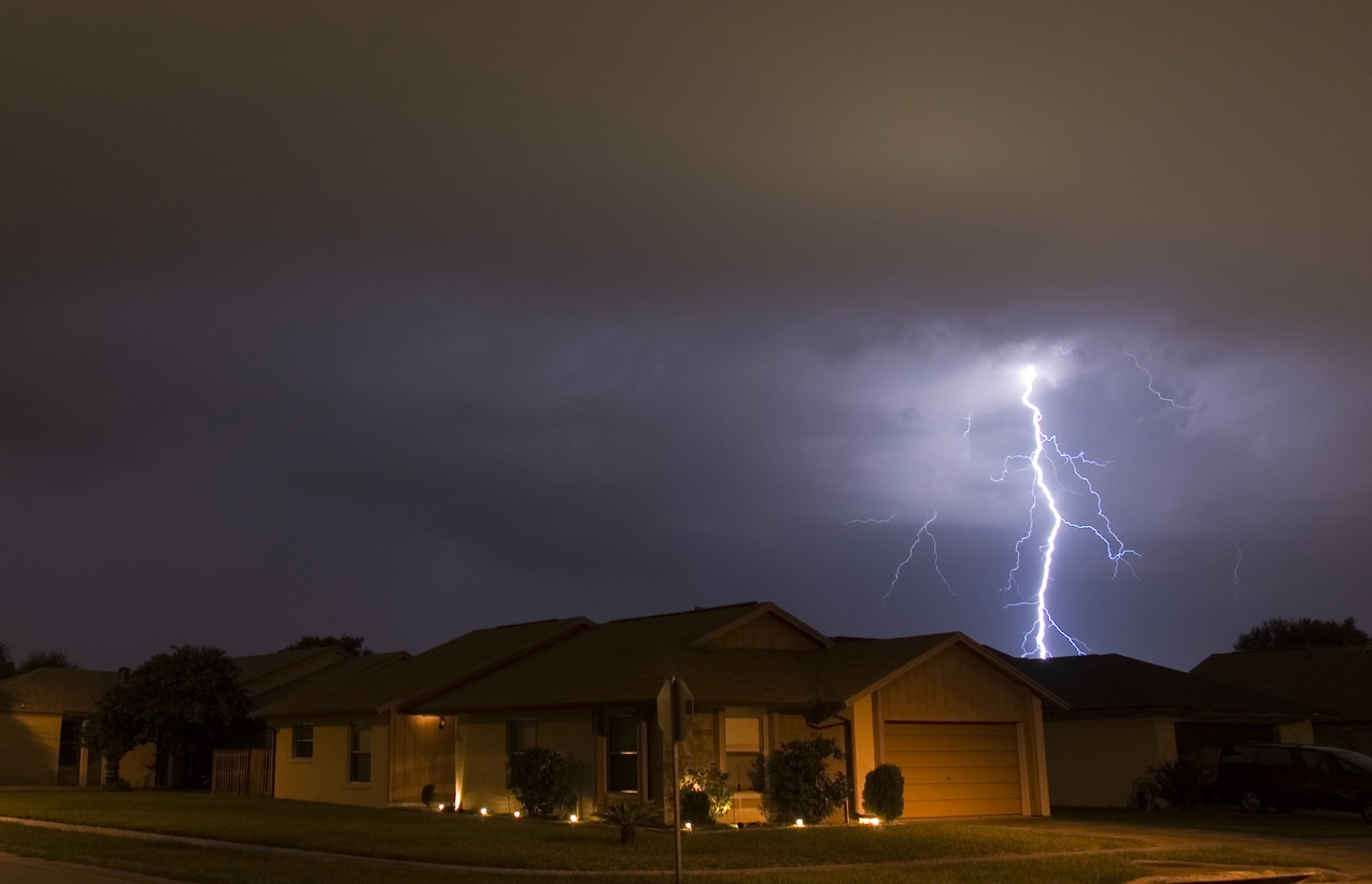 Lightning strikes in the night near family houses