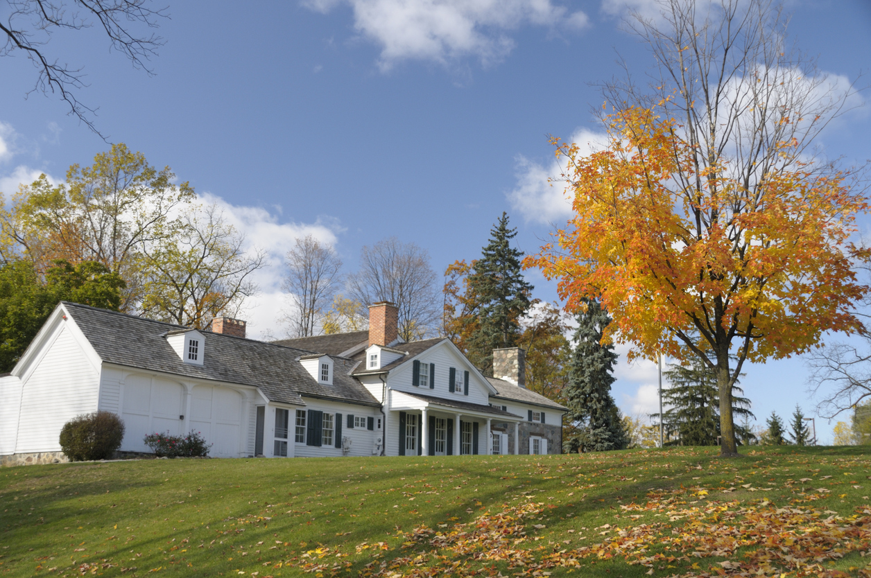 Angled view of white farmhouse on a hill in fall.