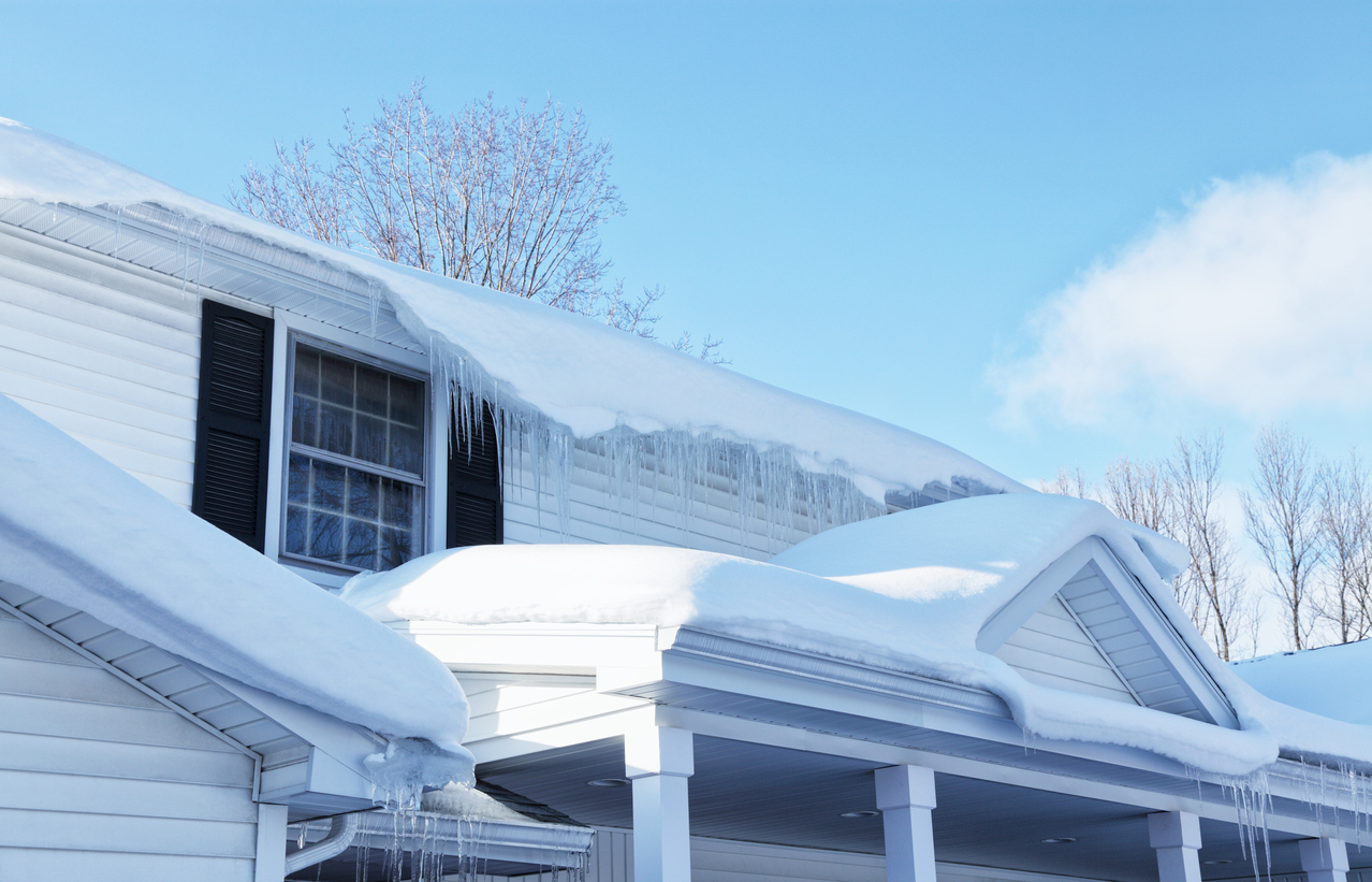 Melting Snow And Icicles On Residential House Roof Edge