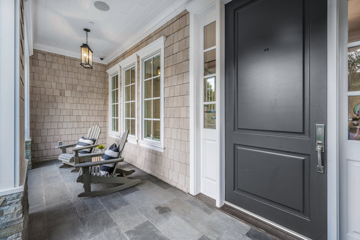 A front porch with a black door in a new construction home