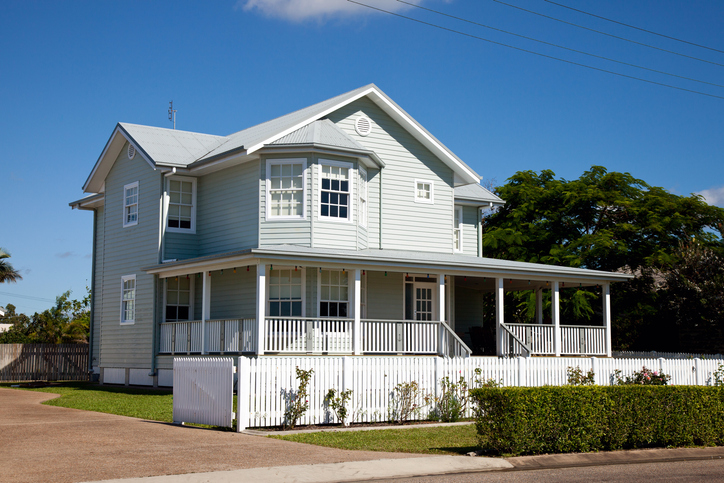 Beautiful colonial home with white picket fence, blue sky and green grass