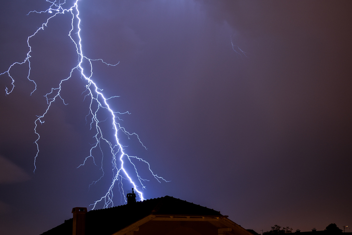Powerful lightning strike above house roof