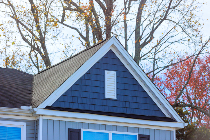 Reveals elegant design of gray house highlighting shingles on roof surrounding, unique architectural details